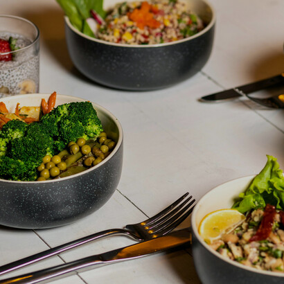 A black ceramic bowl filled with sliced fruits, quinoa, and assorted fresh vegetables — a vibrant example of a low-calorie meal combination