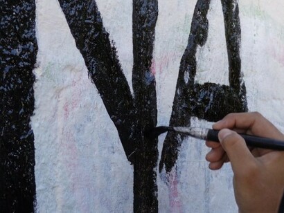 Una mano en pleno proceso de escritura sobre una pared blanca