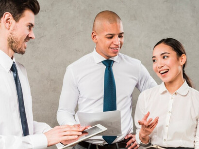 A group of young professionals share ideas in front of a concrete wall — a moment of collaboration in a modern work setting
