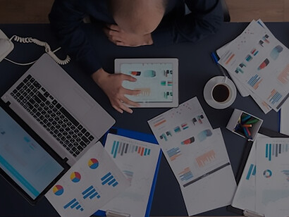 Top view of businessman using tablet pc analyzing financial charts and documents, sitting at desk in corporate office