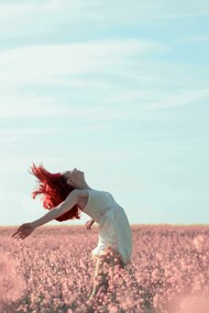 A woman in a yellow dress stands in a field covered with pink petals