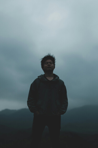 A man wearing a hoodie walks through a misty forest, mirroring the fog of anxiety clouding his mind
