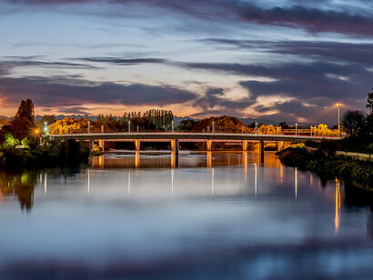Night falls over the Tanaro River in Alessandria, illuminating the calm waters of Piedmont, Italy
