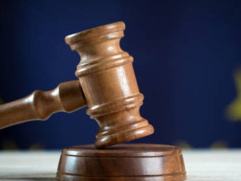 A judge's gavel resting on a book with the EU flag in the background, symbolizing EU regulations and the growing influence of European Union bureaucracy over lifestyle restrictions