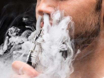 The profile of a young man using a vape