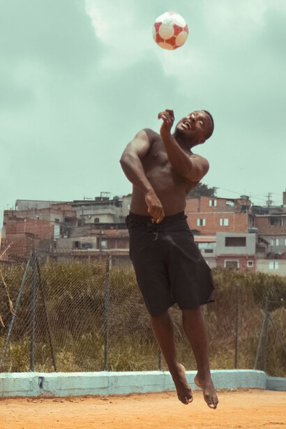 Jogador de futebol brinca com a bola em campo de esportes em seu bairro na comunidade 