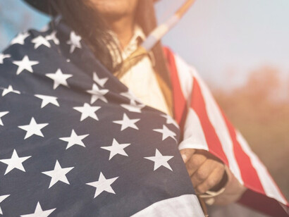 A Native American man in the desert holding an American flag embodies the intersection of American individualism and indigenous heritage
