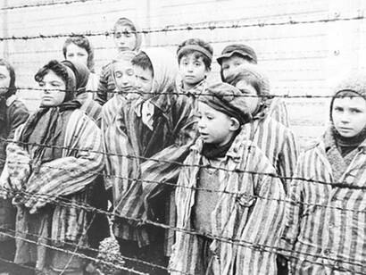 Niños frente a una alambrado del campo de concentración de Auschwitz, Polonia (1941)
