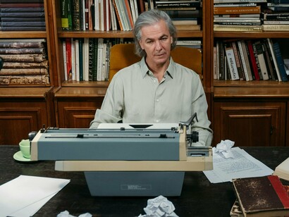 Escritor em fase de pesquisa. Distante e irrealista, por certo… talvez não tanto como possa parecer… Visionário, muito provavelmente… Mas igualmente observador menos enviesado pelo *in the bubble*, talvez mais sólido porque calmo e não necessitado da adrenalina do ofegante repórter ou dos sucessivos directos nas diversas pantalhas que se espalham e empalam tudo à nossa volta… Este eterno errante narrador de mil e uma noites e estórias de encantar terá de permanecer quedo e silente? 