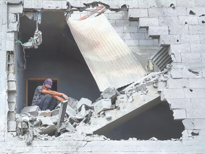 Un joven mira hacia la calle desde el interior de un edificio destruido en Gaza