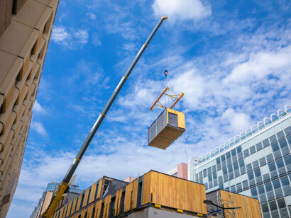 Modular wooden commercial building being assembled with a crane, showcasing efficient prefabricated construction techniques