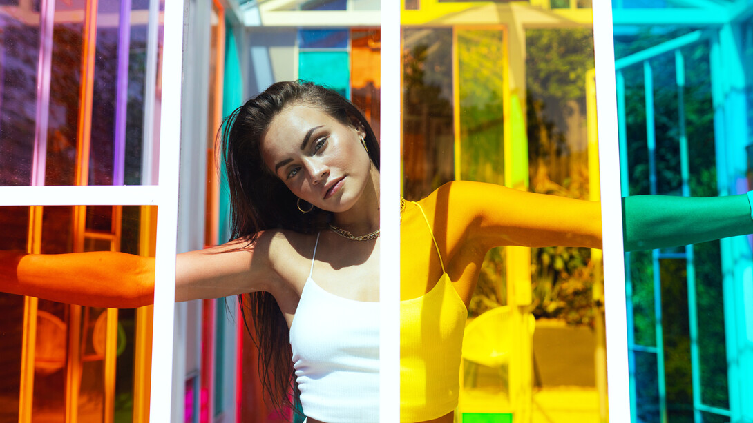 Modelo detrás de una vitrinas de distintos colores. Un color bien elegido puede enfatizar tu mirada, iluminar tu cara o potenciar el brillo de tu cabello