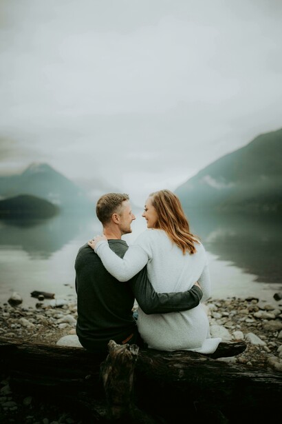 A couple sitting together beside a river in a mountain valley