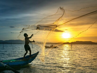 Un vieux pêcheur lance son filet pour attraper du poisson à l'aube