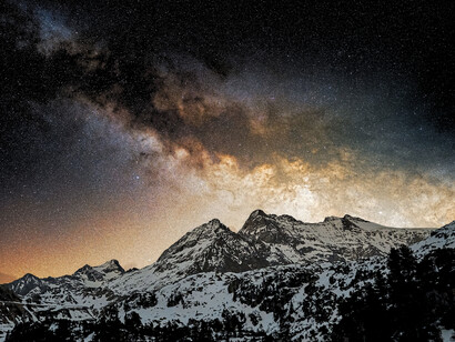 The glowing Milky Way rising above a snowy mountain range, reflecting the breathtaking environments where meteor showers are best observed