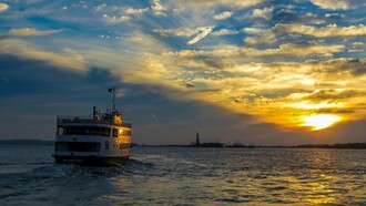 A ferry crossing the harbour toward Ellis Island at sunset, symbolising the hopes and uncertainties carried by those seeking a new beginning