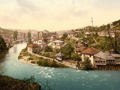 Sarajevo, olhando para Bentbaša. Aqueles que acompanharam as imagens chocantes da Guerra da Bósnia na imprensa internacional, podem se lembrar dos bombardeios pelas forças sérvias posicionadas justamente nas montanhas de Trebević. Em agosto de 1992, a Biblioteca foi o alvo. As chamas consumiram não apenas sua estrutura, mas também cerca de dois milhões de livros e documentos históricos. Uma tragédia cultural sem precedentes, que ainda hoje dói na memória da cidade