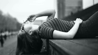 A woman lying down on the street smoking a cigarette