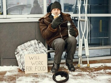 A homeless man eating a simple meal outdoors in winter, representing the fundamental importance of food in the fight against poverty
