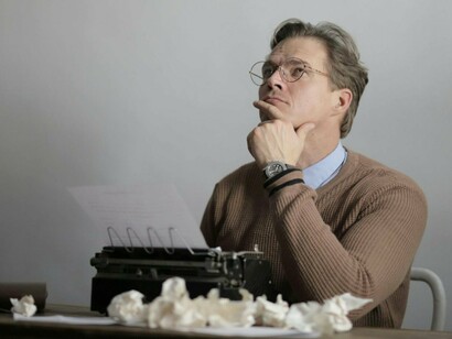 A writer lost in thought above an unfinished page, representing the search for meaning amid uncertainty