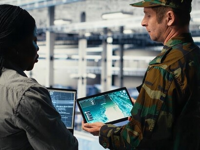 An army commander and a software developer monitor an AI-powered radar system at a data center