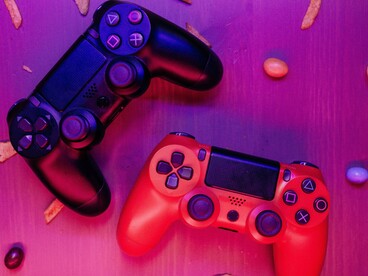 Two video game controllers under vibrant neon lights, representing the entertainment medium often blamed in the aftermath of violent tragedies