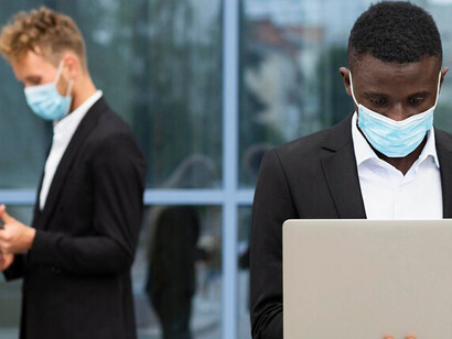 Individuals working during COVID-19, wearing masks and holding laptops, illustrating the shift to remote work and health precautions