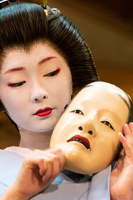 Kyoto geiko Toshimana, adorned in full makeup and a katsura wig, elegantly holds a Nō mask on the picturesque Kawamura Noh Stage, Japan