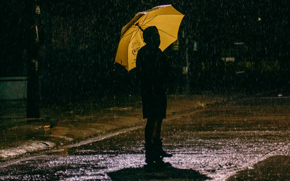 Ein Mann steht mit einem Schirm im Regen