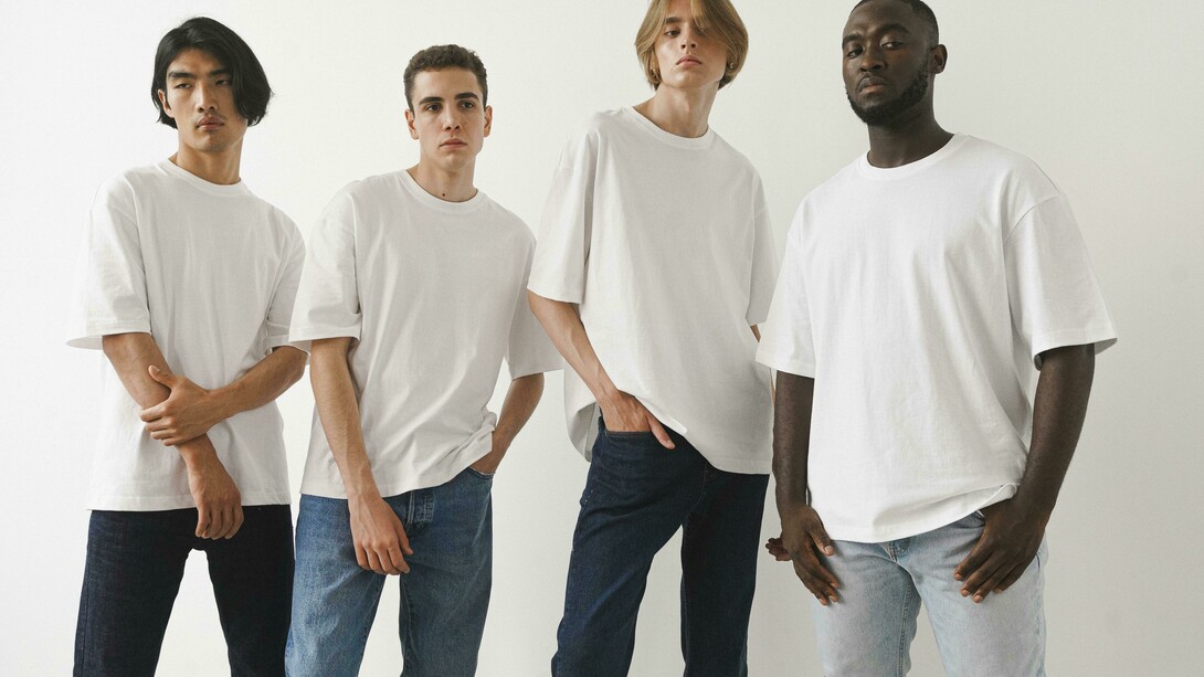 Men posing in classic white T-shirts and jeans against a minimalist backdrop