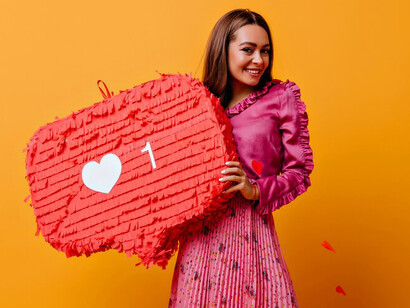 A woman holding a thumbs-up decoration in her hands, smiling proudly