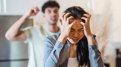 A distressed woman holds her head in frustration, illustrating the emotional toll of psychological abuse in a relationship