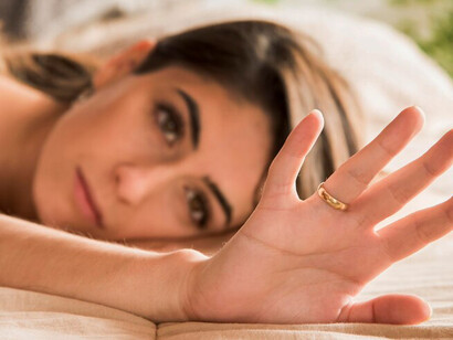 A blurred woman clutches a wedding ring, her face filled with sadness, as loneliness and heartbreak surround her