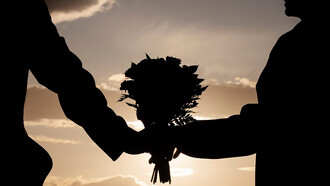 Side view of a couple holding a bouquet of flowers together