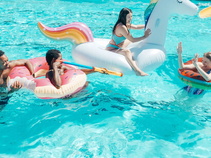 The friends are playing and having a good time on their inflatables in the swimming pool