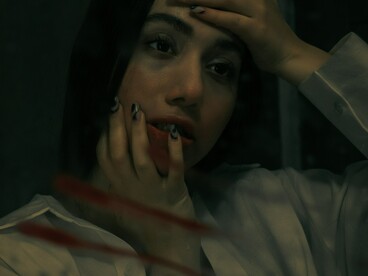 A sad woman standing in front of a mirror, lost in quiet reflection