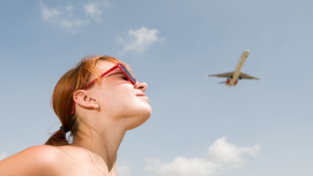 Young woman watching an airplane in the sky, feeling a sense of longing