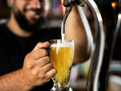 A bartender skillfully pours beer from a keg into a glass, ensuring the perfect balance of foam and liquid