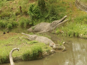 As esculturas do Dinosaur Trail aparecem integradas à paisagem de Crystal Palace Park. A permanência dessas representações lembra como os animais extintos continuam presentes no imaginário humano, mesmo quando a evolução não segue uma trajetória de progresso em direção às espécies atuais