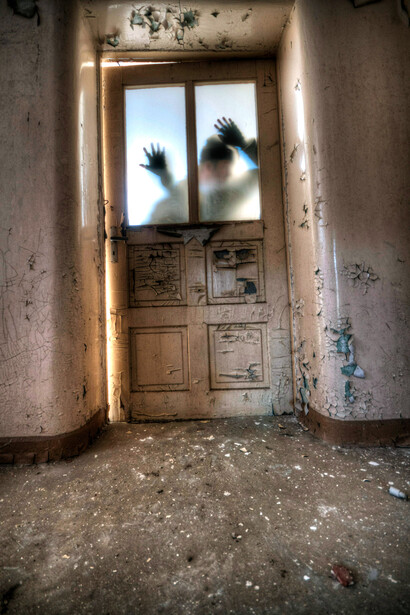 Un espectro apoyado en la puerta en el interior de una casa. Las leyendas urbanas se cuentan en todo el mundo, adoptando diferentes formas y matices