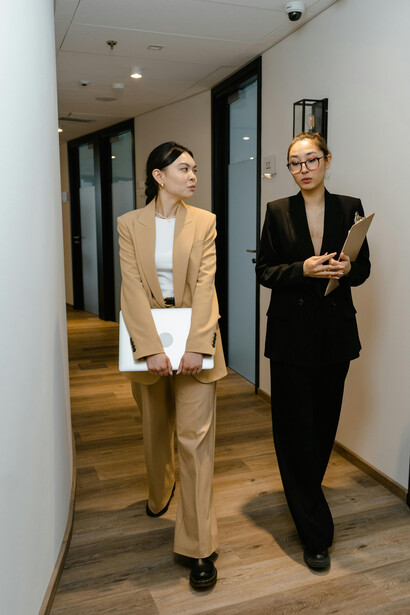 Women dressed in business casual clothing walk through a corridor while talking