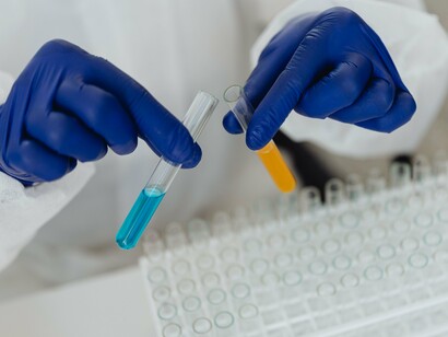 Pesquisador segura um recipiente com material de estudo em um ambiente de laboratório equipado para investigação científica. Transformar conhecimento em aplicações práticas exige um percurso que vai da bancada de pesquisa até a sociedade