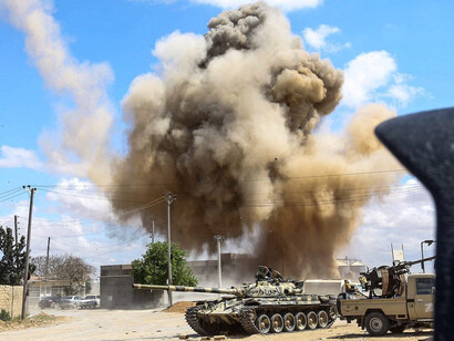 Una columna de humo se eleva desde un ataque aéreo detrás de un tanque y camiones que pertenecen a las fuerzas leales al Gobierno de Acuerdo Nacional de Libia