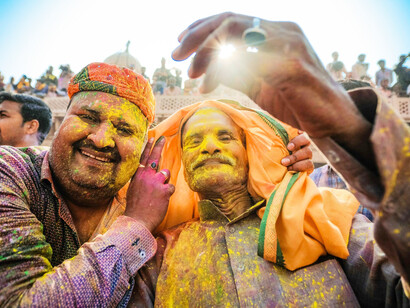 A man in a green and brown long-sleeve shirt celebrates the vibrant Holi Festival 2020 in Vrindavan, Uttar Pradesh, India