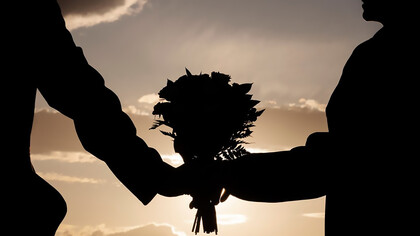 Side view of a couple holding a bouquet of flowers together