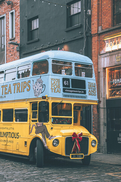 An old blue-and-yellow double-decker bus on a rain-damp cobblestone street in Dublin, Ireland