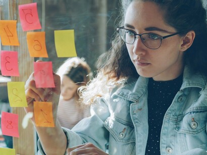 A young woman placing notes on a planning board, symbolising the role of young voices in developing solutions for a changing climate