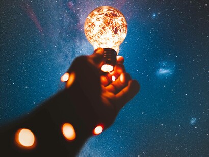 A person holding a lightbulb to the sky