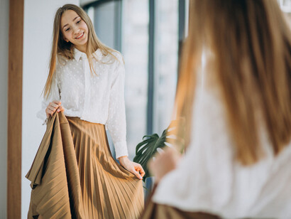 A young woman in a casual outfit looks into the mirror with confidence