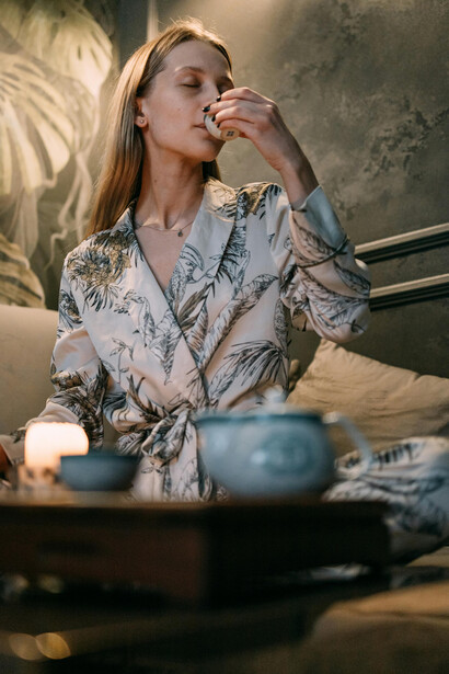 A woman sits on a couch, meditating in a calm indoor space with soft, natural light